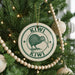 A Christmas tree decorated with ornaments, including a circular ornament with a kiwi bird design and the text "KIWI" around the edge.