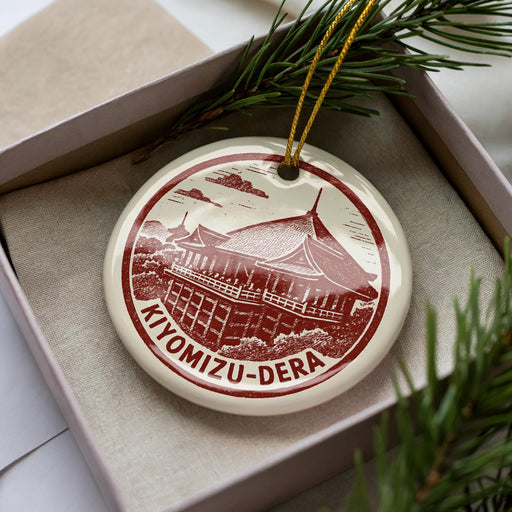 A decorative ornament in a box, featuring a red and white design of a temple or pagoda with the text "Kiyomizu-Dera" on it.