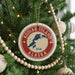 A Christmas tree decorated with ornaments, including a circular ornament with the text "KODIAK ISLAND USA" and a map of Alaska.