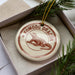 A decorative ornament in a box, featuring a komodo dragon illustration.