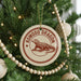 A Christmas tree decorated with ornaments, including a circular ornament with a red and white design featuring a komodo dragon.
