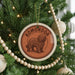 A Christmas tree decorated with ornaments, including a circular ornament with a picture of a shaggy dog and the word "KOMONDOOR" written on it.