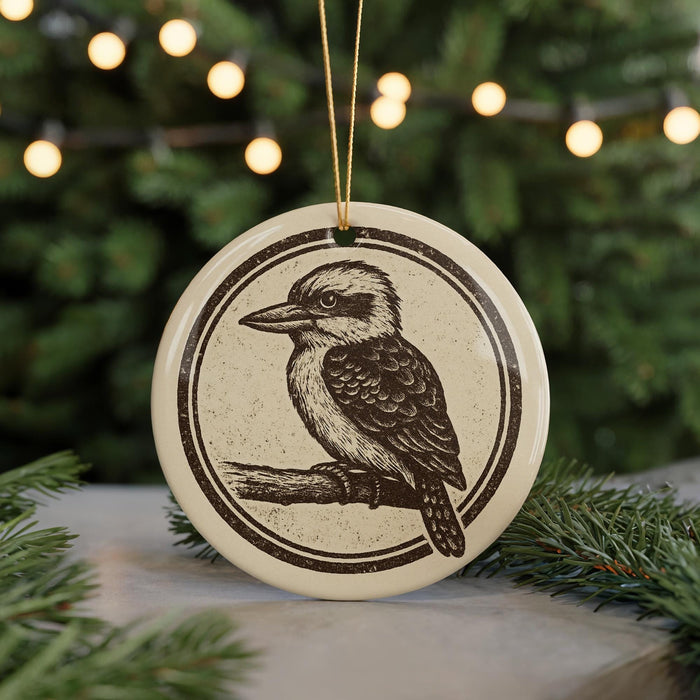 A round ornament featuring a black and white illustration of a bird perched on a branch, with a string attached to it.