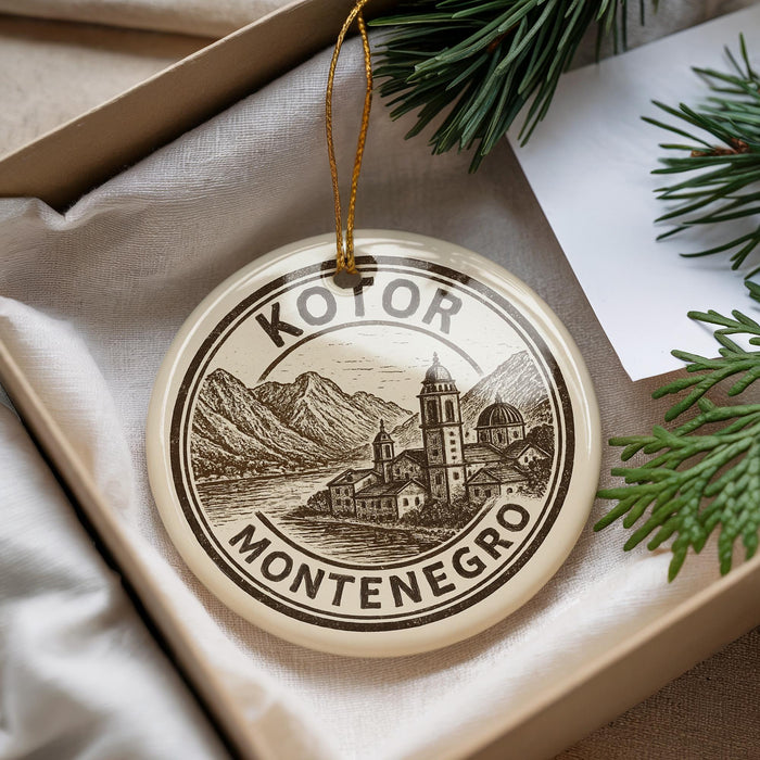 A circular ornament with the text "KOTOR MONTENEGRO" printed on it, surrounded by a decorative string and pine branches.