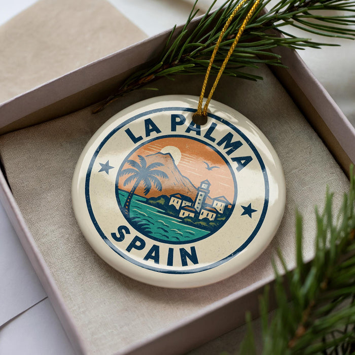 A circular ornament with the text "LA PALMA SPAIN" and a tropical landscape design, hanging from a string.