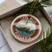 A circular ornament with a picture of Lake Bled, Slovenia, surrounded by a border.