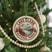 A round ornament on a Christmas tree, featuring a design of Lake Clark National Park with mountains and a lake.
