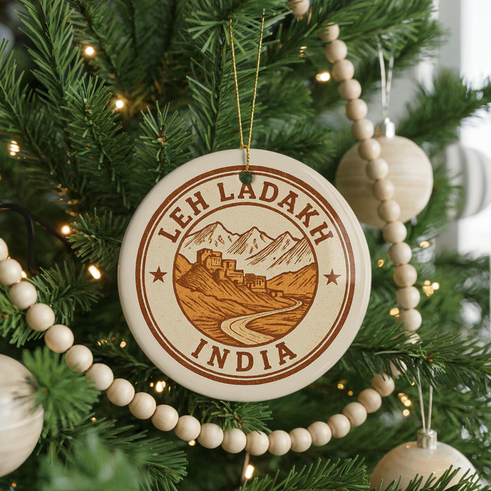 A Christmas tree decorated with ornaments, including a circular ornament with the text "LEH LADAKH INDIA" and a mountain landscape design.