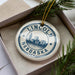 A circular ornament with the text "LINCOLN NEBDAKA USA" printed on it, hanging from a string.