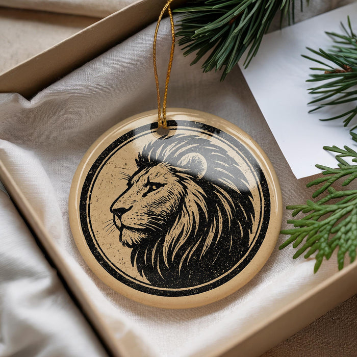 A decorative ornament featuring a lion's head is displayed in a box, surrounded by pine branches and greenery.