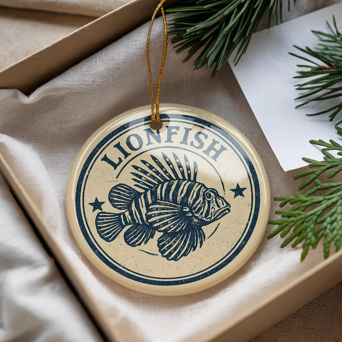 A circular ornament with a lionfish design, hanging from a string, placed inside a box with pine branches.