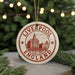 A circular ornament with the text "LIVERPOOL ENGLAND" and an illustration of a city skyline, hanging from a string.