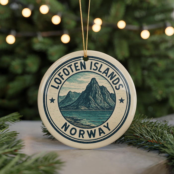 A circular ornament with the text "Lofoten Islands NORWAY" and a mountain illustration, hanging from a string against a blurred background of Christmas lights.