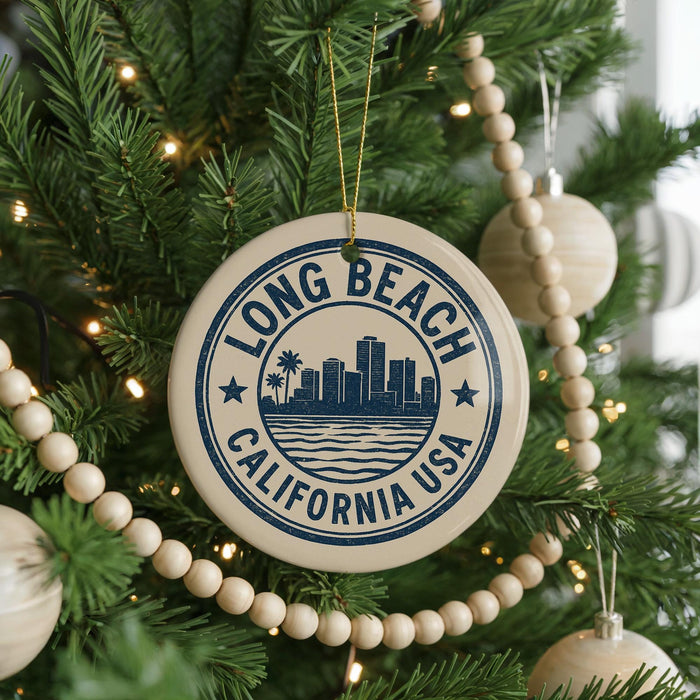 A circular ornament on a Christmas tree with the text "LONG BEACH CALIFORNIA USA" printed on it, surrounded by other ornaments and lights.