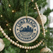 A circular ornament on a Christmas tree with the text "LONG BEACH CALIFORNIA USA" printed on it, surrounded by other ornaments and lights.