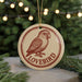 A round ornament with a bird image and the word "LOVEBIRD" written on it, hanging from a string.