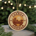 A circular ornament with the text "LUANDA ANGOLA" and a silhouette of a city skyline, hanging from a string.