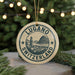 A circular ornament with the text "LUGANO SWITZERLAND" and an illustration of a Swiss mountain range, hanging from a string.