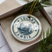 A circular ornament with the text "LUSAKA ZAMBIA" printed on it, surrounded by a decorative border.