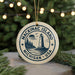 A circular ornament with a lighthouse and trees, surrounded by Christmas lights.