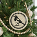 A Christmas tree decorated with ornaments, including a circular ornament featuring a black and white bird design.