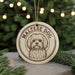 A circular ornament featuring a Maltese dog's face, with the text "MALTESER DOG" printed on it, is displayed in front of a blurred Christmas tree.