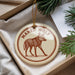 A circular ornament with a brown illustration of a wolf and the text "MANED WOLF" on it, hanging from a string.