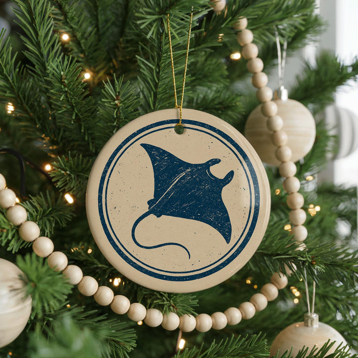 A Christmas tree decorated with ornaments, including a circular ornament with a blue stingray design and a string of wooden beads.