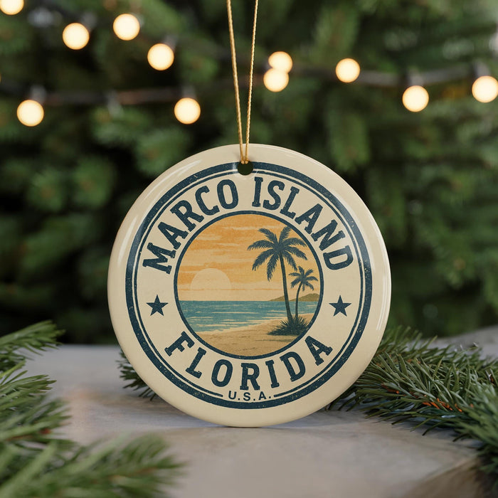 A circular ornament with the text "MARCO ISLAND FLORIDA" and a palm tree design, hanging from a string against a background of Christmas lights and greenery.