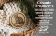 Ceramic ornaments, specifically a round ornament with a cat image, are displayed in a basket with a pine branch.