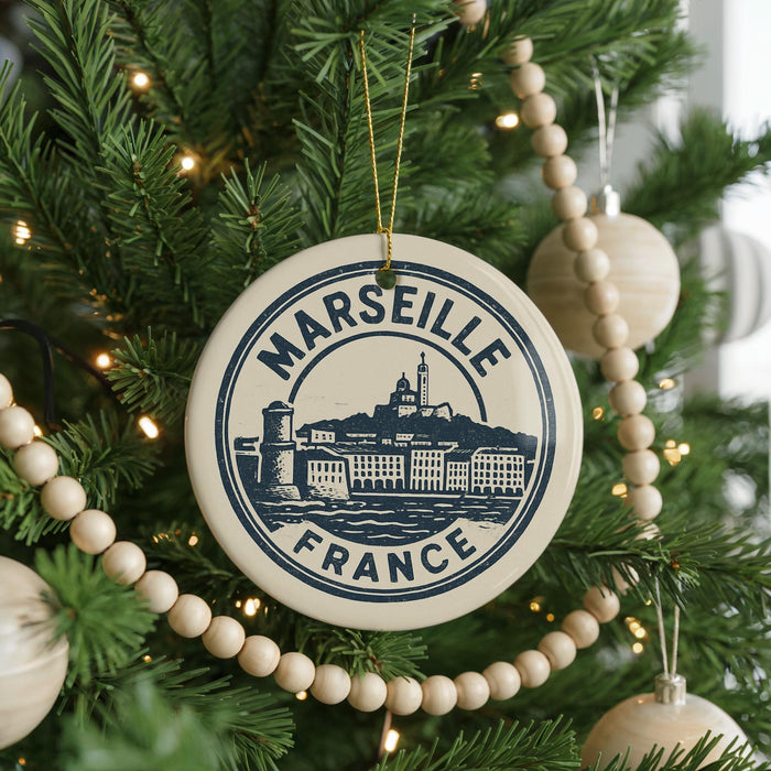 A Christmas tree decorated with ornaments, including a circular ornament with the text "MARSÉILLE FRANCE" and a castle illustration.