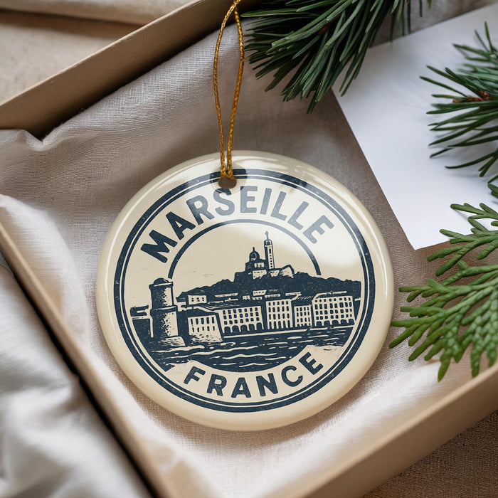 A circular ornament with the text "MARSEILLE FRANCE" and an illustration of a cityscape, hanging from a string.