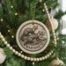 A Christmas tree decorated with ornaments, including a circular ornament with a drawing of two martens and the word "MARTENS" written on it.