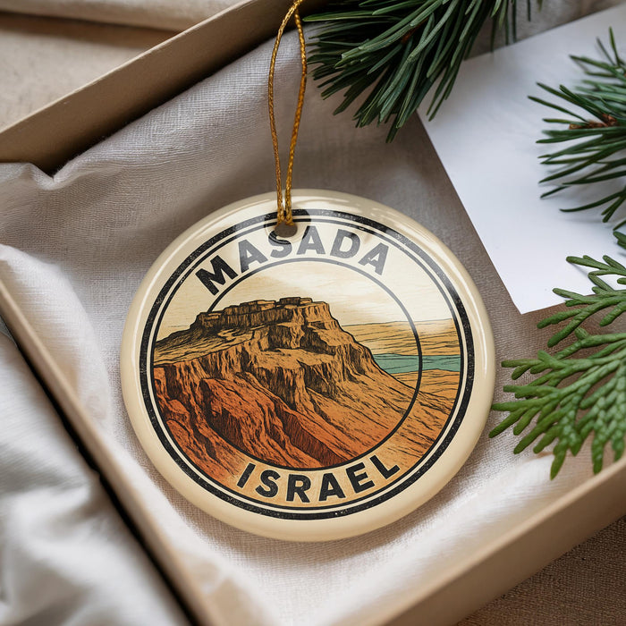 A circular ornament with the text "MASADA ISRAEL" and an illustration of a mountain range, hanging from a string.