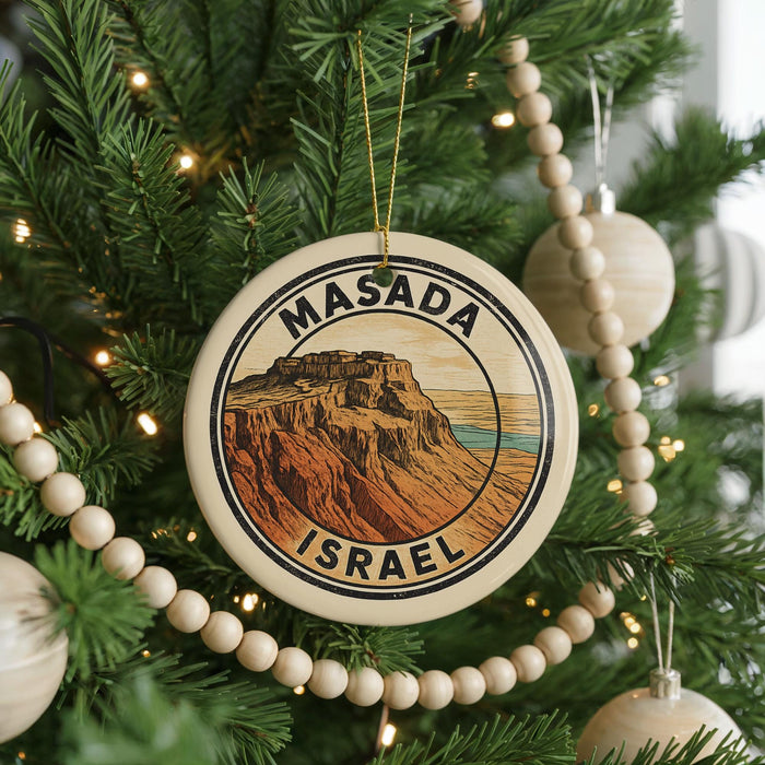A circular ornament on a Christmas tree, featuring an illustration of Masada, the historic city of Jerusalem, with the text "MASADA ISRAEL" prominently displayed.