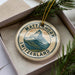 A circular ornament with the text "MATTERHORN SWITZERLAND" and an illustration of a mountain, placed in a box with pine branches.
