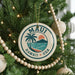 A circular ornament on a Christmas tree with the text "MAUI HAWAII USA" and a palm tree design.