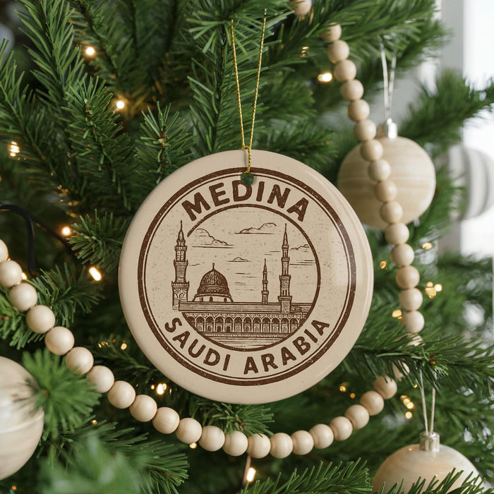 A Christmas tree decorated with ornaments, including a circular ornament with the text "MEDINA SAUDI ARABIA" and a mosque illustration.