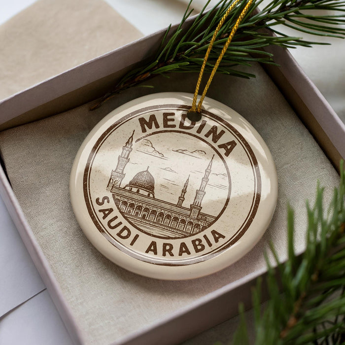 A circular ornament with the text "MEDINA SAUDI ARABIA" printed on it, surrounded by pine branches.