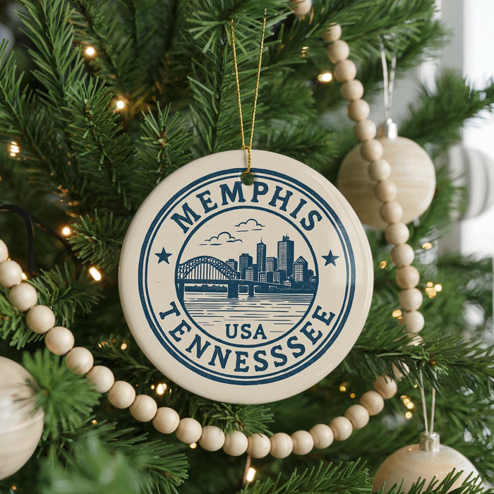 A Christmas tree decorated with ornaments, including a circular ornament with the text "Memphis, Tennessee USA" and a bridge in the background.