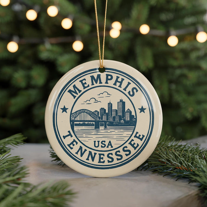 A circular ornament with the text "MEMPHIS TENNESSEE USA" and a graphic of a bridge and skyline, hanging from a string.
