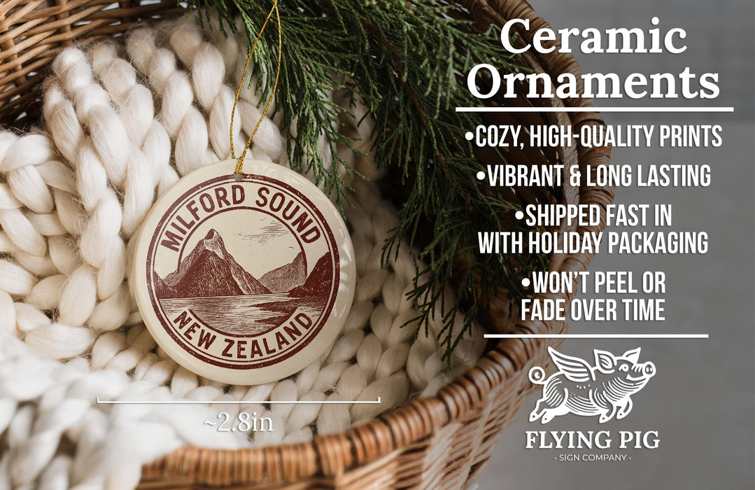 Ceramic ornaments, specifically Milford Sound New Zealand ornaments, are displayed in a woven basket. The ornaments are described as cozy, high-quality prints, vibrant, and long-lasting, and are shipped fast in holiday packaging. They are not to be peeled or faded over time. The image also includes a scale for the ornaments and a logo for the Flying Pig sign company.