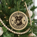 A round ornament with a dog's head and the text "MINIATURE SCHNAUZER" is hanging on a Christmas tree.