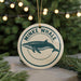 A round ornament with a graphic of a whale and the text "MINKE WHALE" on it, hanging from a string.