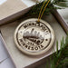 A circular ornament with the text "MINNEAPOLIS USA" printed on it, surrounded by a pine branch and a white box.