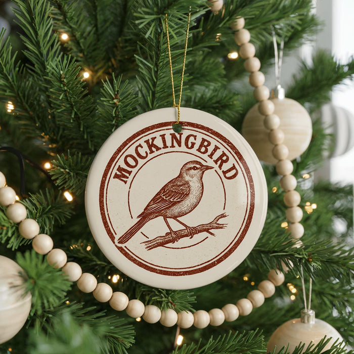 A Christmas tree decorated with ornaments, including a circular ornament with a bird design and the text "MOCKINGBIRD" on it.