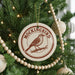 A Christmas tree decorated with ornaments, including a circular ornament with a bird design and the text "MOCKINGBIRD" on it.
