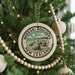 A circular ornament on a Christmas tree, featuring the text "MOERAKI BOULDERS NEW ZEALAND" and an illustration of a rocky landscape.