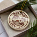 A circular ornament with the text "MOLOKAI HAWAII USA" printed on it, surrounded by pine branches.