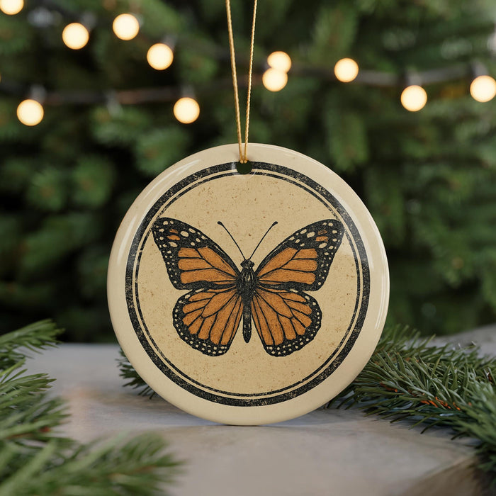 A circular ornament featuring a detailed illustration of a butterfly is displayed against a blurred background of greenery and twinkling lights.
